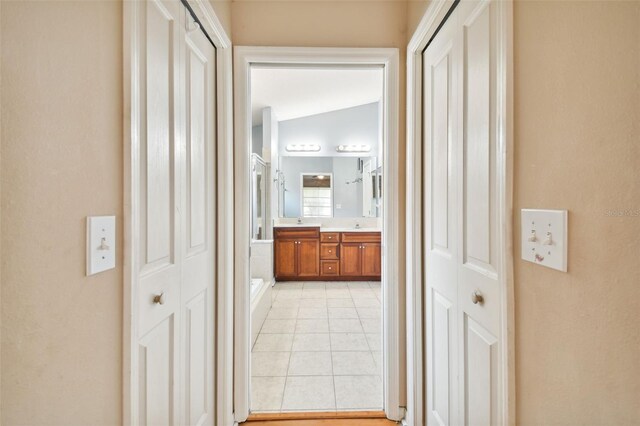 hall with vaulted ceiling and light tile patterned floors