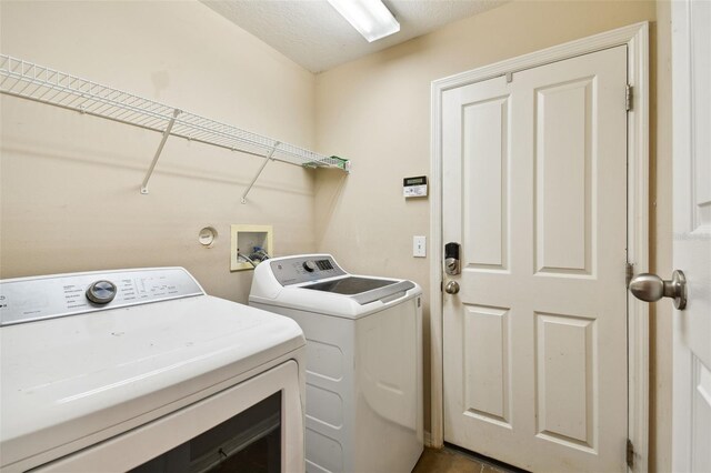 laundry room with a textured ceiling and washer and dryer