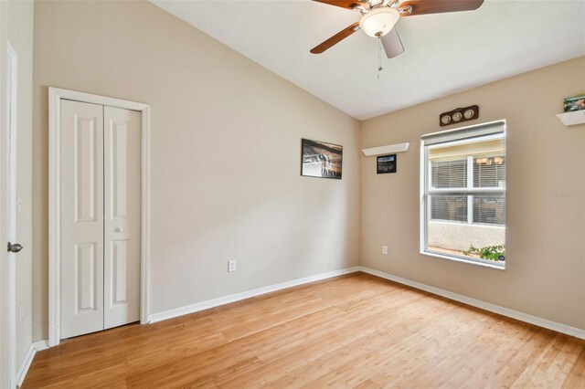 spare room featuring light wood-type flooring, vaulted ceiling, and ceiling fan