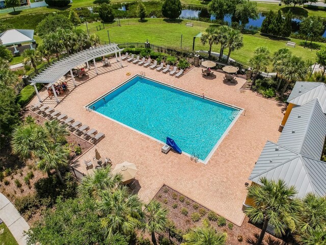 view of pool with a patio, a water view, and a lawn