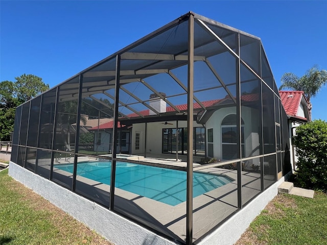 view of pool with glass enclosure, ceiling fan, and a patio