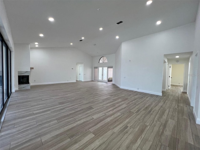 unfurnished living room featuring high vaulted ceiling and a premium fireplace