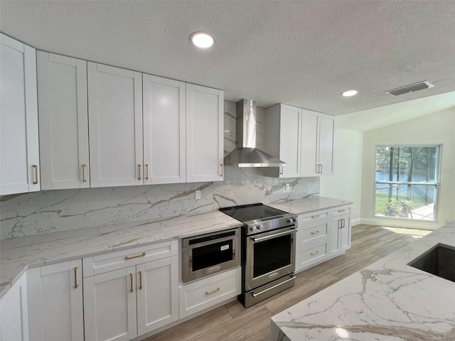 kitchen featuring lofted ceiling, stainless steel electric stove, a textured ceiling, white cabinets, and wall chimney exhaust hood