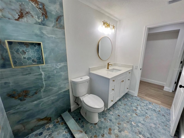 bathroom featuring a textured ceiling, toilet, and vanity