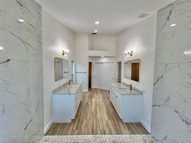 bathroom with vanity, a towering ceiling, a textured ceiling, and hardwood / wood-style floors