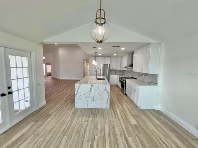 kitchen featuring stainless steel appliances, backsplash, wall chimney range hood, pendant lighting, and white cabinets