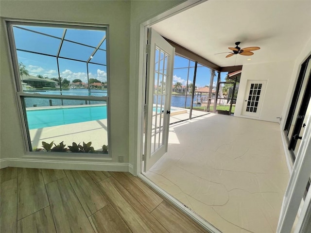 doorway to outside with a water view and ceiling fan