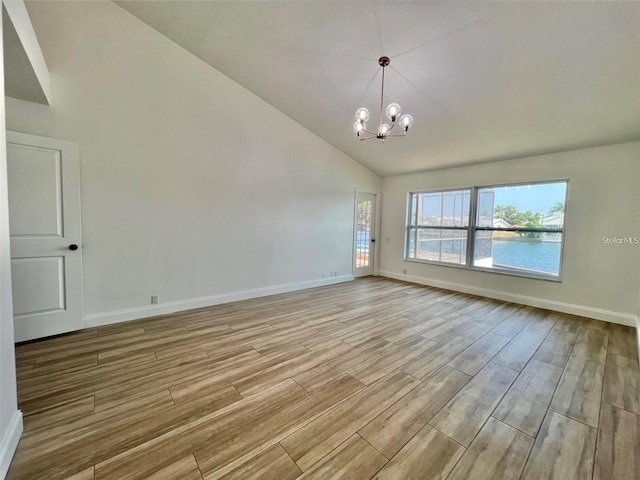 spare room with a water view, a notable chandelier, and high vaulted ceiling