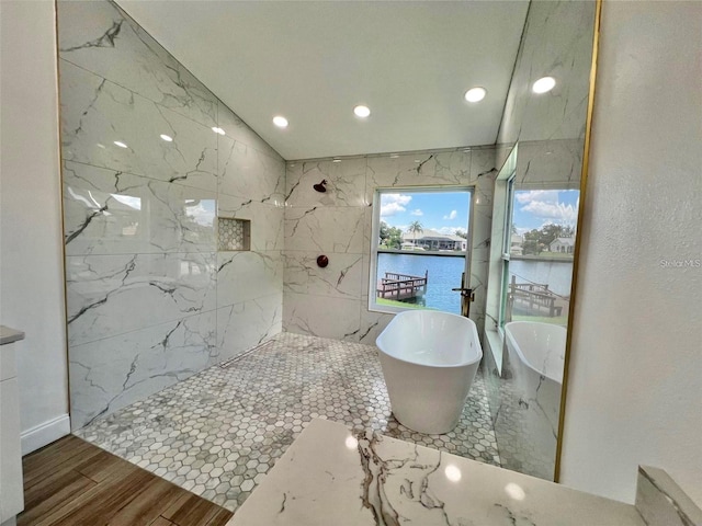 bathroom featuring a water view, vaulted ceiling, and separate shower and tub