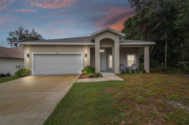 view of front of house featuring driveway, a lawn, an attached garage, and stucco siding