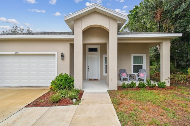 view of front of home featuring concrete driveway, a porch, an attached garage, and stucco siding