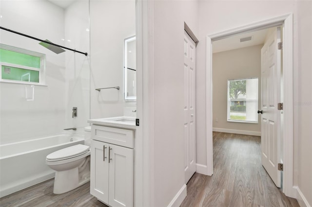 bathroom with baseboards, bathing tub / shower combination, toilet, wood finished floors, and vanity