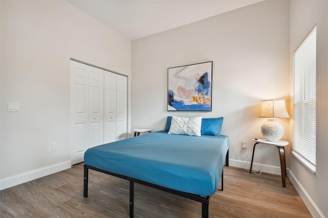 bedroom with a closet, baseboards, and wood finished floors