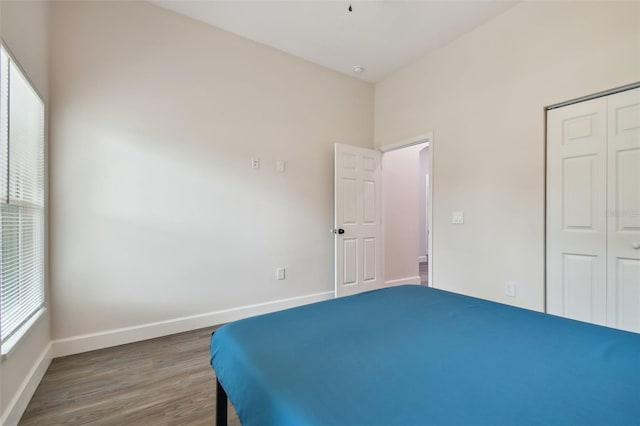 unfurnished bedroom with a closet, wood finished floors, and baseboards