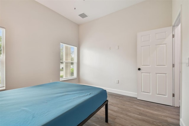 bedroom featuring multiple windows, wood finished floors, visible vents, and baseboards