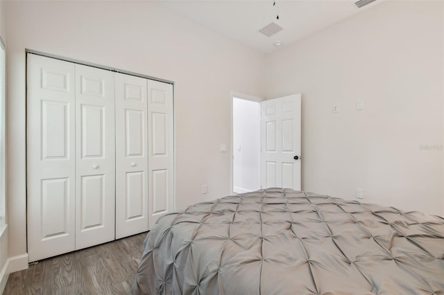 bedroom with a closet, visible vents, and wood finished floors