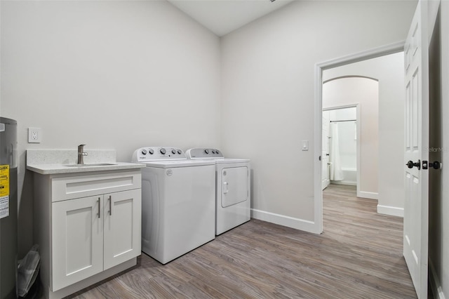 laundry area featuring cabinet space, baseboards, light wood-type flooring, separate washer and dryer, and a sink