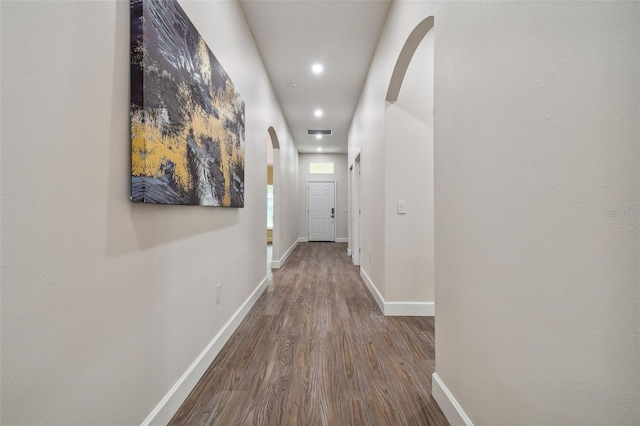 hallway with arched walkways, recessed lighting, baseboards, and wood finished floors