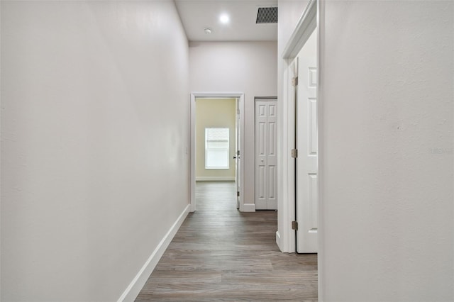 corridor featuring visible vents, baseboards, and wood finished floors