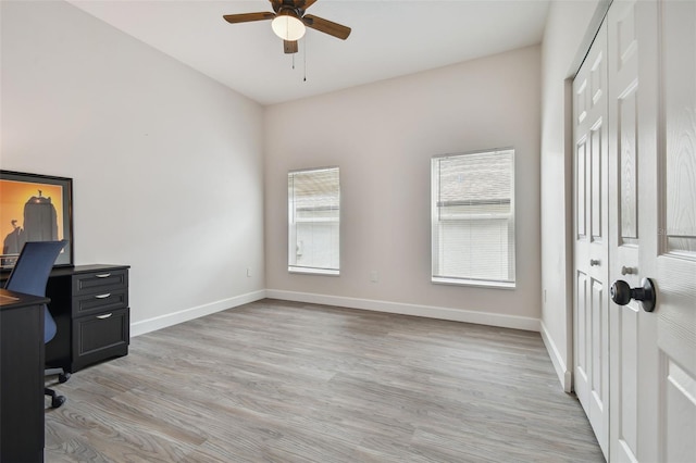 office space with light wood-style floors, ceiling fan, and baseboards