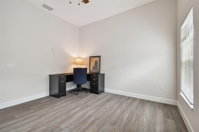 home office featuring light wood finished floors, baseboards, visible vents, and ceiling fan