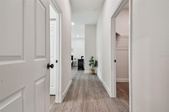 corridor with light wood-style flooring and baseboards