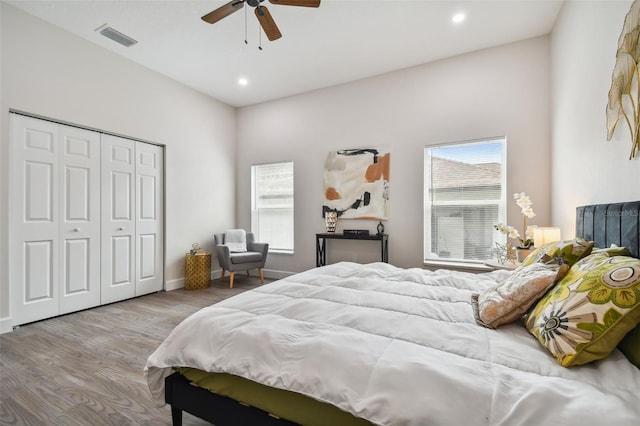 bedroom with a closet, multiple windows, visible vents, and wood finished floors