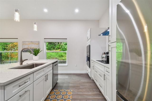 kitchen featuring stainless steel appliances, hanging light fixtures, a sink, and white cabinets