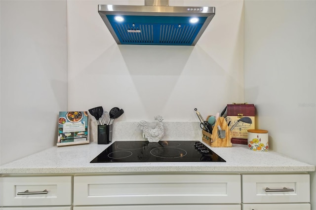 kitchen featuring light stone countertops, black electric cooktop, and white cabinetry