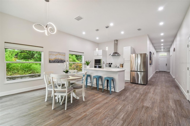 kitchen featuring visible vents, white cabinetry, light countertops, appliances with stainless steel finishes, and wall chimney range hood