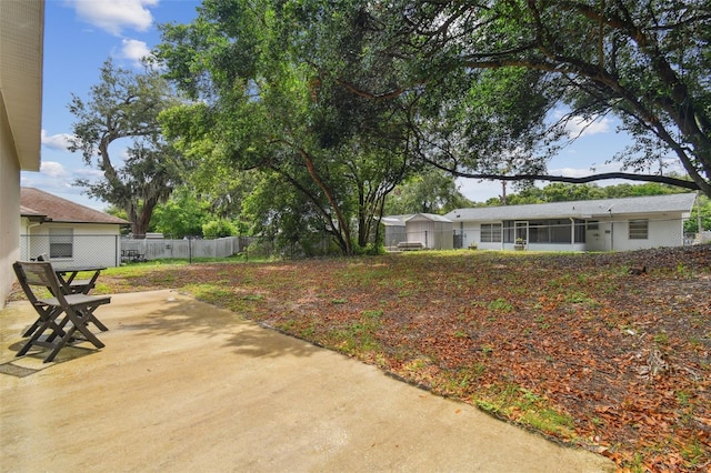 view of yard featuring a sunroom, a patio area, and fence