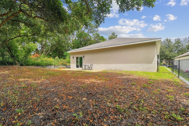 view of side of property featuring a patio area, a fenced backyard, a gate, and stucco siding