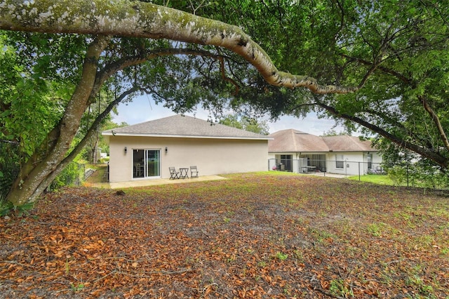 rear view of house with fence and stucco siding