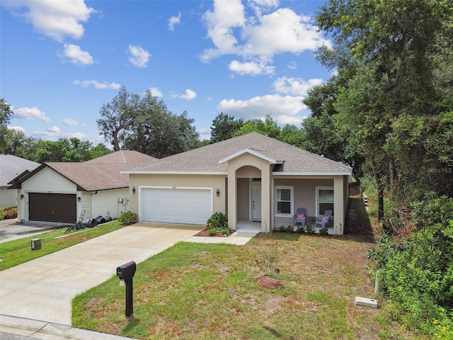 ranch-style house with driveway, stucco siding, roof with shingles, an attached garage, and a front yard