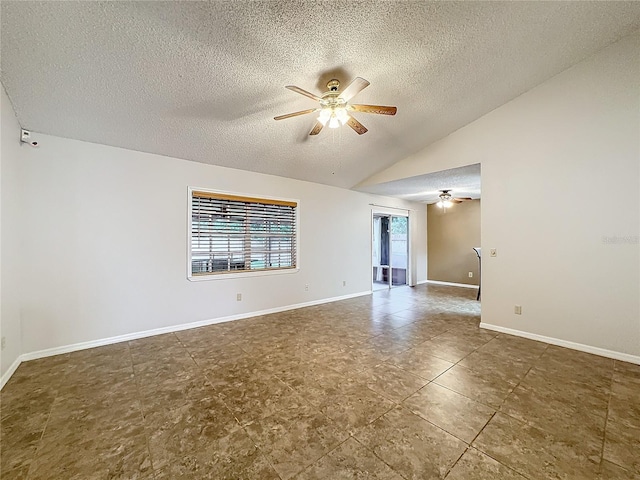 empty room with a ceiling fan, vaulted ceiling, a textured ceiling, and baseboards