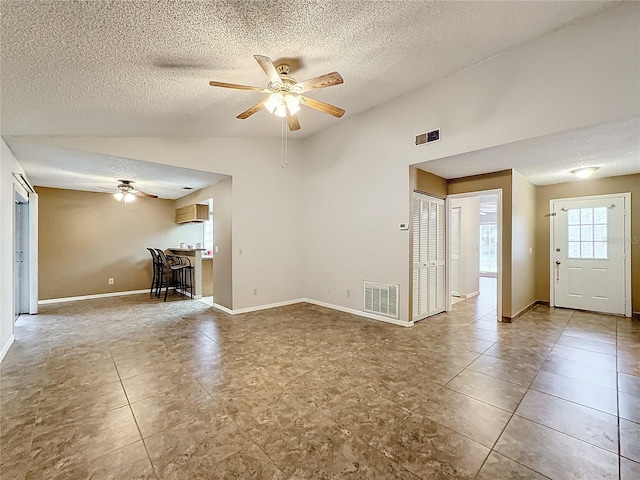 unfurnished living room featuring lofted ceiling, baseboards, visible vents, and a ceiling fan