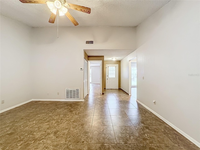 spare room featuring a textured ceiling, visible vents, and baseboards