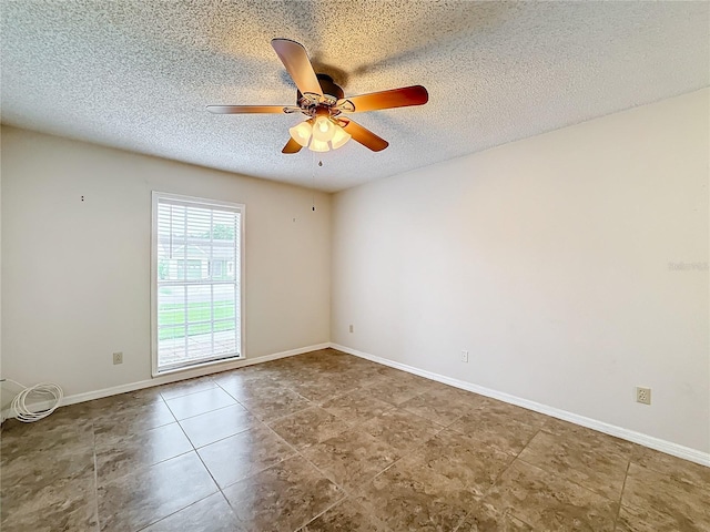 empty room with a ceiling fan, baseboards, and a textured ceiling