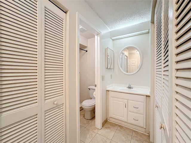 bathroom featuring toilet, tile patterned floors, a textured ceiling, vanity, and a closet