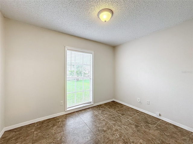 unfurnished room with baseboards and a textured ceiling