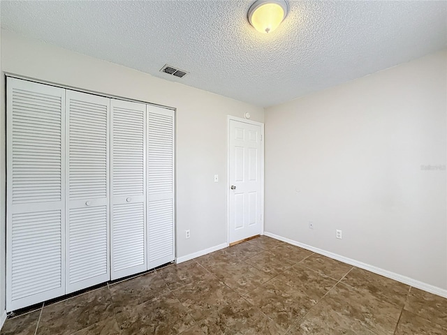 unfurnished bedroom featuring baseboards, a textured ceiling, visible vents, and a closet