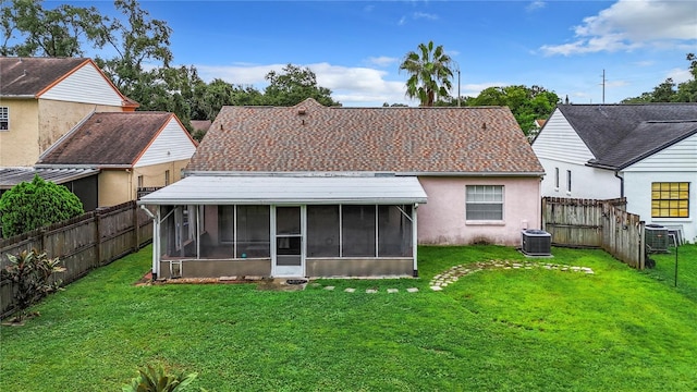 rear view of house featuring central AC unit, a lawn, a fenced backyard, and a sunroom