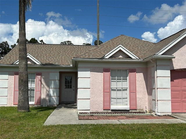 view of front facade with a garage, a shingled roof, a front yard, and stucco siding