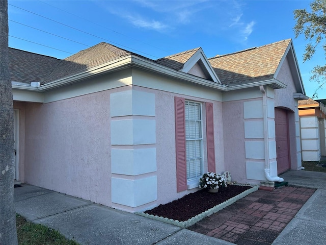 view of property exterior featuring a garage, a shingled roof, and stucco siding