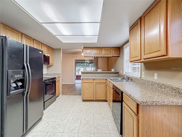 kitchen featuring light tile patterned floors, a peninsula, light countertops, black appliances, and a sink