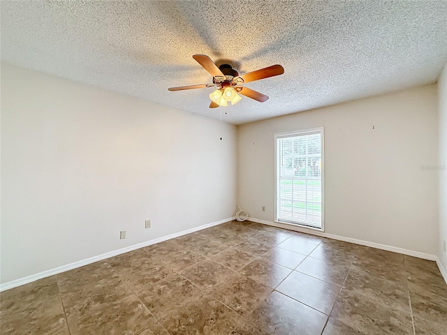 tiled empty room featuring a textured ceiling, a ceiling fan, and baseboards