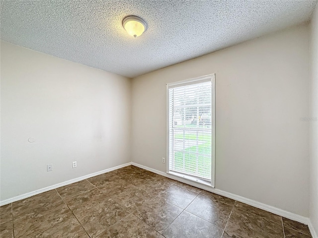 unfurnished room featuring a textured ceiling and baseboards