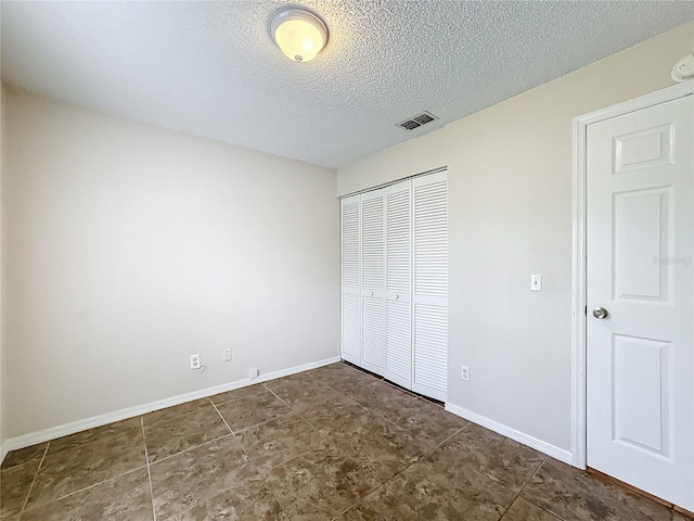 unfurnished bedroom featuring baseboards, a textured ceiling, visible vents, and a closet