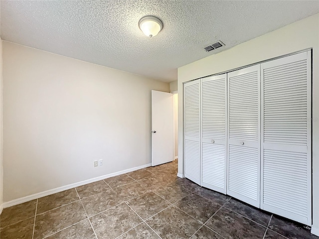 unfurnished bedroom featuring a closet, visible vents, a textured ceiling, and baseboards