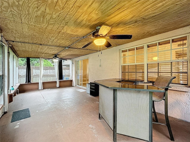 unfurnished sunroom featuring wood ceiling and a ceiling fan